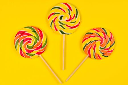 Colorful candy on a yellow  background. Lollipop. Top view. Copy space.の写真素材