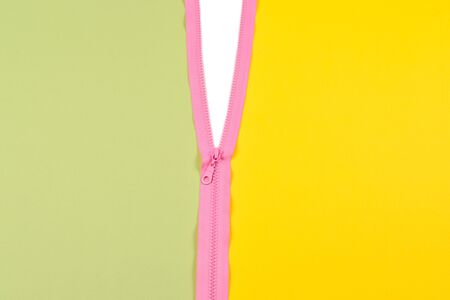 Pink zipper splits green and yellow background isolated.の写真素材