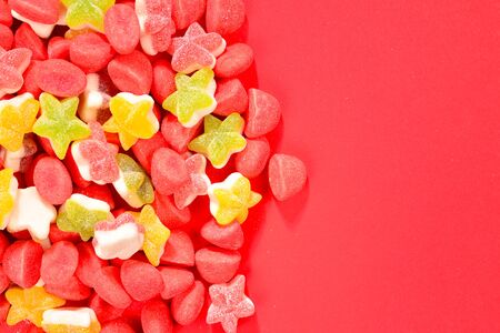 Assorted colorful gummy candies and lollipop on red background. Top view. Jelly  sweets.の写真素材