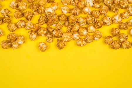Caramel pop corn on yellow background. Copy space.