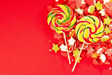 Assorted colorful gummy candies and lollipop on red background. Top view. Jelly  sweets.の写真素材