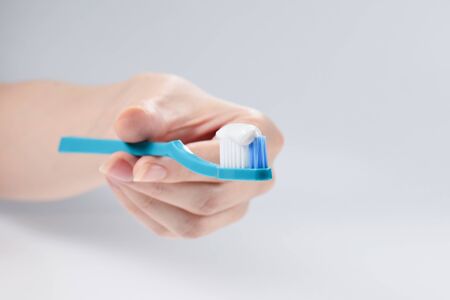 Woman holds toothbrush with toothpaste in her hand isolated on white background.