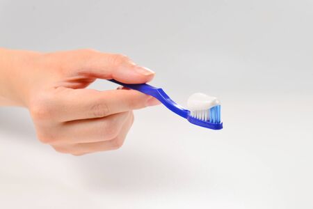 Woman holds toothbrush with toothpaste in her hand isolated on white background.