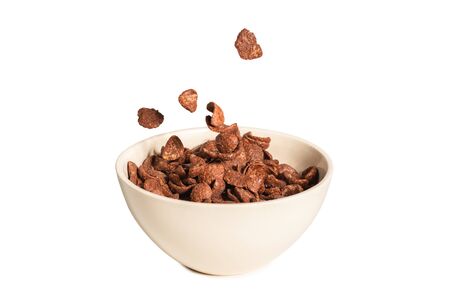 Chocolate corn flakes falling to the white bowl isolated on white. Motion Copyspace.