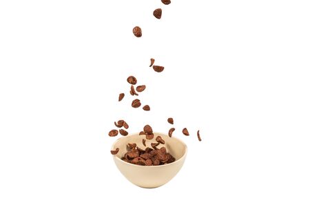 Chocolate corn flakes falling to the white bowl isolated on white. Motion. Copyspace.の写真素材
