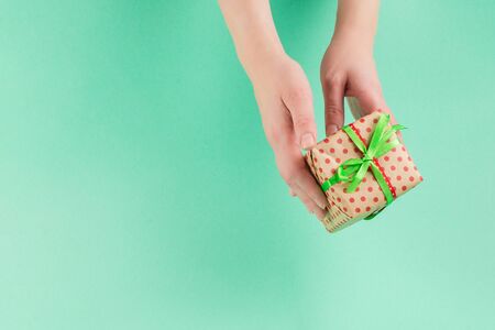 Present in woman hand on a green background. Copy space.の写真素材
