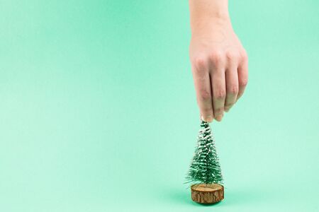 Small christmas tree in woman hand on a green background. Copy space.の写真素材