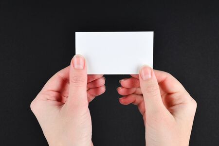 Empty card in woman hand  on a black background. Copy space.