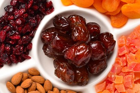 Mix of dried fruits and nuts. Apricot, raisin, cranberry, dates fruit. Isolated on a white...