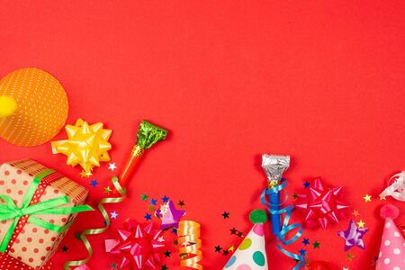 Festive golden and purple stars of confetti  and a present, birthday caps on a red background. Space for text or design.の写真素材