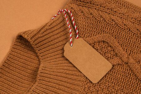 Brown tag on brown knitted sweater. Copy space.