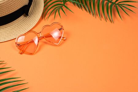 Pink sunglasses and a hat on orange background. Copy space. 