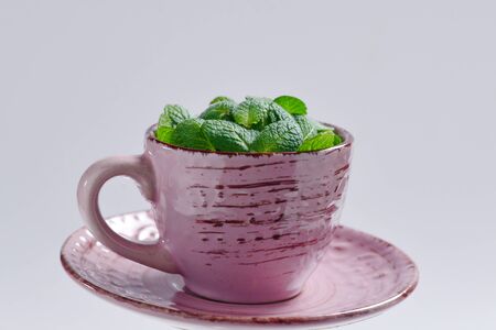 Mint leaves in a cup isolated on white background.