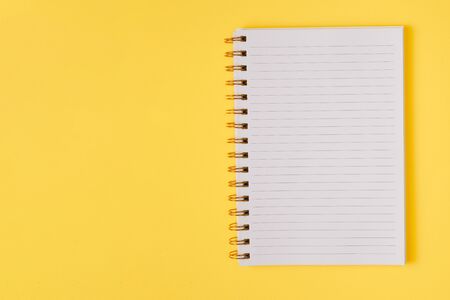 Open empty notebook on a yellow background. Top view. Space for text or design. の写真素材