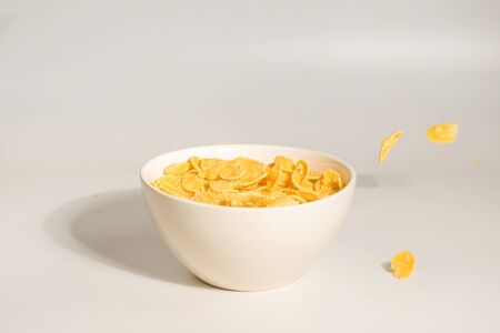 Corn flakes falling to the white bowl. Motion. Copyspace. Isolated on white. 