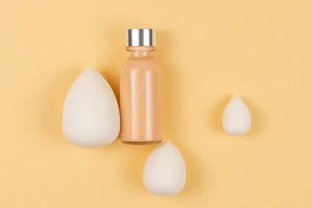 Small, medium and large  white beauty blender and makeup foundation on beige background.