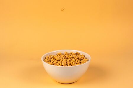 Honey rings cereal box for morning breakfast. Corn flakes falling to the white bowl. Motion. Copyspace.の写真素材