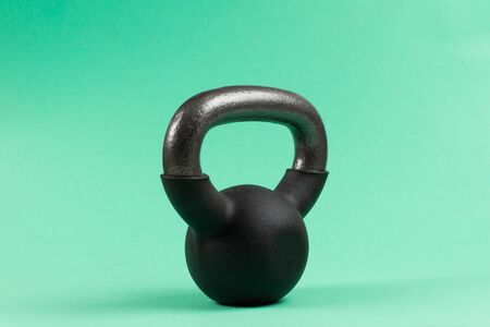 Black weight on green background. 4 kg weight. Fitness for women.の写真素材