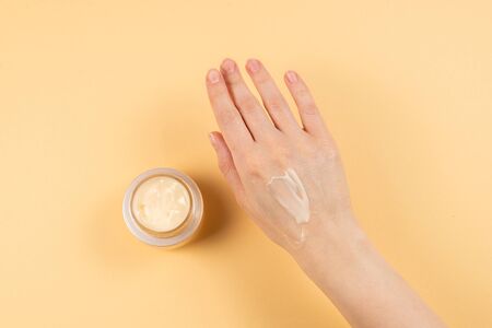 Hand cream and woman hands on a beige background. Copy space. 