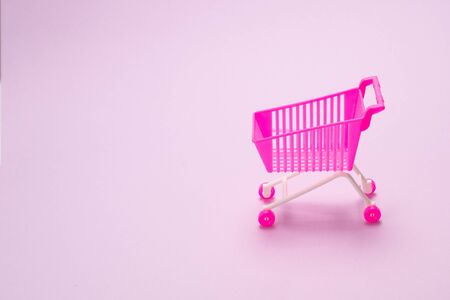 Blue present box with pink bow in a shopping cart on a pink background. の写真素材