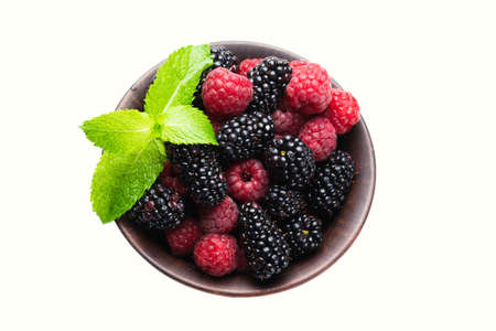 Raspberry, blackberry and mint leaf in ceramic brown bowl isolated on white background.
