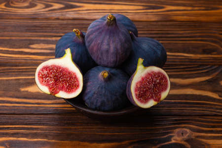 Tasty figs in a bowl on wooden background. Top view. Slices.