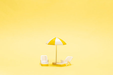 Sun lounger and yellow umbrella on a yellow background.の写真素材