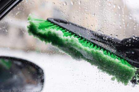 Snow removal, car in snow. Woman cleans the car from snow.の写真素材