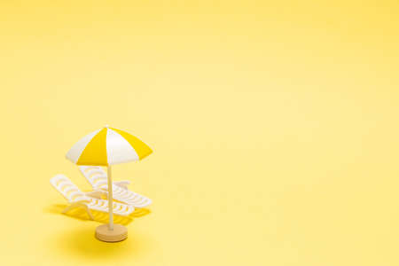 Two sun loungers and a red umbrella on a yellow background. Copy space.の写真素材
