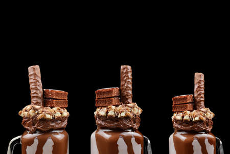 Chocolate extreme milkshake with brownie cake, chocolate paste and sweets. Crazy freakshake food trend. Copy spaceの写真素材