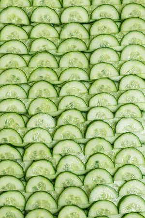 Fresh green slices of cucumber as background. Top view.の写真素材