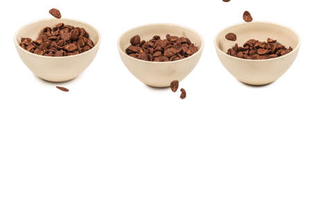 Chocolate corn flakes falling to the white bowl isolated on white. Motion. Copyspace.の写真素材