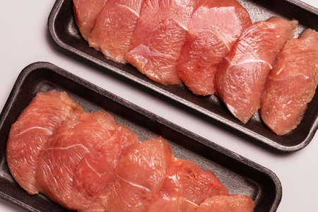 Turkey fillet in a black plastic container isolated on a white background.