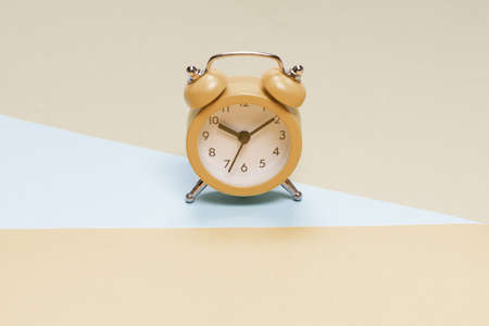 Yellow alarm clock on a yellow, blue and green background. Copy space. Time concept.