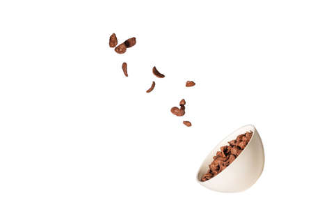 Chocolate corn flakes falling to the white bowl isolated on white. Motion. Copyspace.
