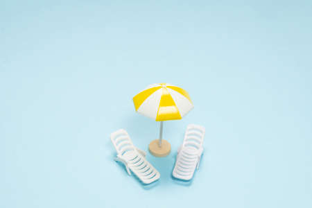 Travel concept. Sun lounger, yellow umbrella on a blue background. Copy space.