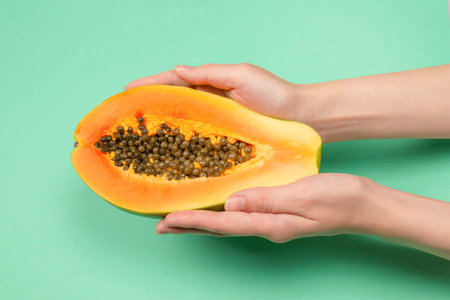 Papaya fruit on a green background in woman hands. Tropical fruit. Half papaya.の写真素材