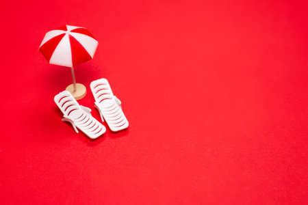 Two sun loungers and red umbrellas on a red background. Copy space.の写真素材