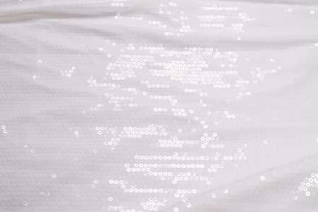 White sequin background. White shiny sequin fabric. Top view.