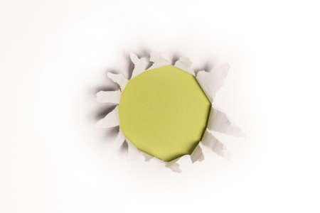 A hole in a white paper on a green background, copy space.の写真素材