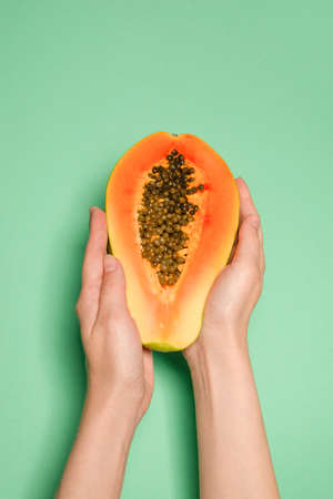 Papaya fruit on a green background in woman hands. Tropical fruit. Half papaya.の写真素材