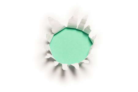 A hole in a white paper on a green background, copy space.の写真素材
