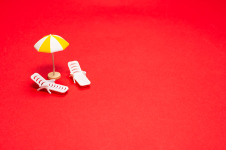 Two sun loungers and red umbrellas on a red background. Copy space.の写真素材