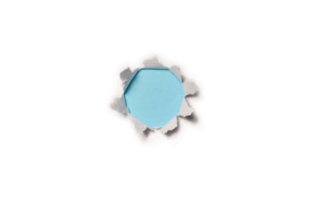 A hole in a white paper on a blue background, copy space.