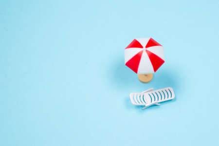 Travel concept. Sun lounger, red umbrella on a blue background. Copy space.の写真素材