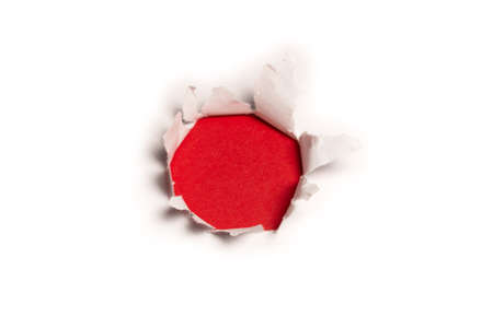 A hole in a white paper on a red background, copy space.の写真素材