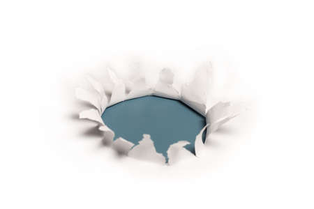 A hole in a white paper on a blue background, copy space.の写真素材