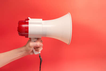 Megaphone in woman hands on a red background. Copy space.の写真素材