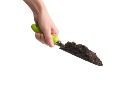 Little green shovel with soil in woman hand isolated on white background.
