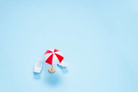 Travel concept. Sun lounger, red umbrella on a blue background. Copy space.